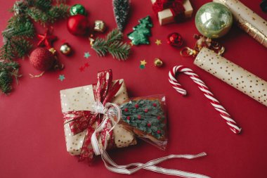 Mutlu Noeller! Şık bir Noel hediyesi, kurabiye, altın ambalaj kağıdı, kurdele ve kırmızı arka planda şenlikli süslemeler. Noel hediyesi paketleme konsepti. İyi tatiller.