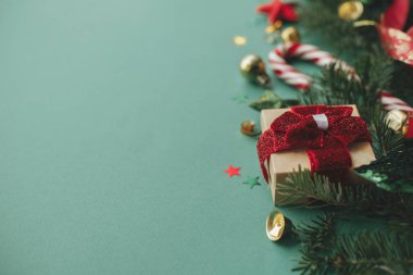 Modern Noel afişi. Şenlikli süslemeler, konfetiler, köknar dalları, yeşil arka planda hediyeler. Mutlu Noeller! Mevsimler tebrik kartı şablonu, metin için boşluk