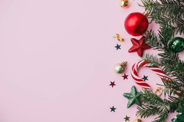 Modern Noel Yatağı. Şık Noel süslemeleri, konfetiler, pembe arka planda köknar dalları. Mutlu Noeller ve mutlu tatiller! Creative Seasons tebrik kartı, metin için boşluk