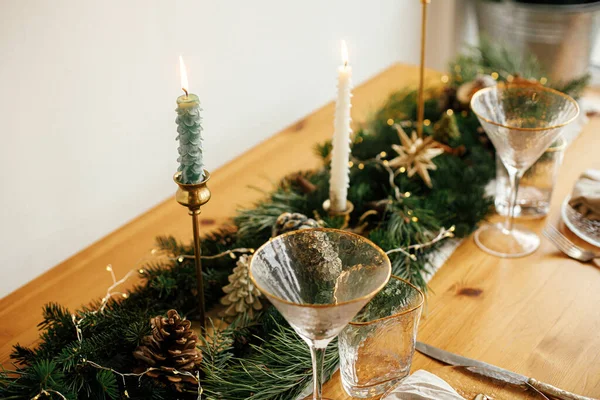 クリスマステーブルのセッティング 皿の上に鐘を持つリネンナプキン ヴィンテージカトラリー テーブルの上に黄金のライトと松のコーンとモミの枝 テーブルの休日の配置 — ストック写真