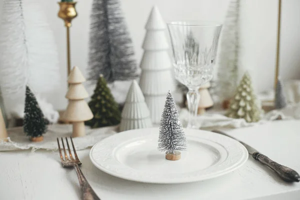 現代のクリスマステーブルの設定 プレート上のスタイリッシュな小さなクリスマスツリー ヴィンテージのカトラリー お祝いのモミや白素朴なテーブルの上の家 テーブルの休日の配置 — ストック写真