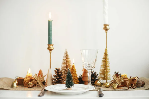 スタイリッシュなクリスマステーブルの設定 皿の上の小さなクリスマスツリー ヴィンテージのカトラリー ワイングラス 現代の黄金のクリスマスツリーとテーブルの上のキャンドル 休日のブランチ 新年のお祝い — ストック写真