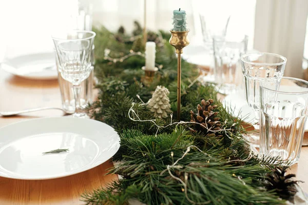 クリスマステーブルのセッティング プレート上のローズマリーの枝 ヴィンテージのカトラリー キャンドル テーブルの上に黄金のライトと松のコーンとモミの枝 雰囲気休日の配置 — ストック写真