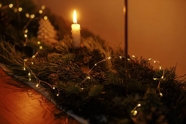 傍晚时分 桌上放着时尚的圣诞烛台 上面有冷杉枝条和金色的灯光 大气中的圣诞节或新年前夕 有金色灯光和松木装饰的忧郁夜景 — 图库照片