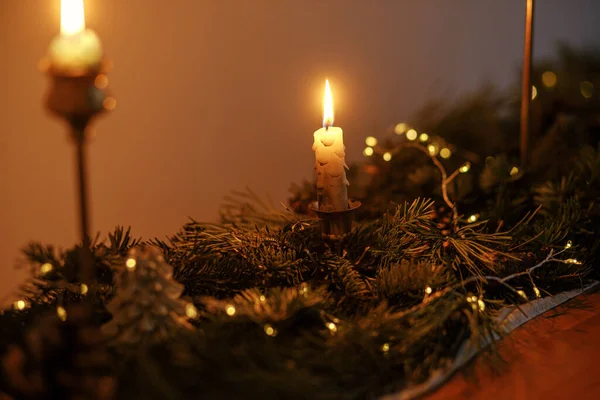 傍晚时分 桌上放着时尚的圣诞烛台 上面有冷杉枝条和金色的灯光 大气中的圣诞节或新年前夕 有金色灯光和松木装饰的忧郁夜景 — 图库照片