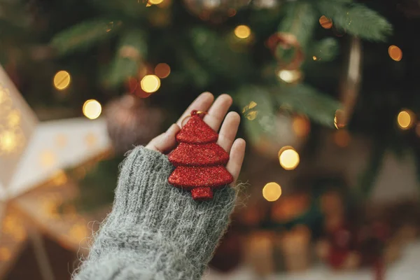 Kézfogás Piros Karácsonyfa Háttérben Megvilágított Arany Fények Díszítő Karácsonyfa Kezében — Stock Fotó