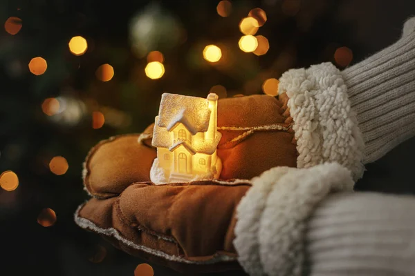 Hands Gloves Holding Little Glowing House Background Illuminated Christmas Tree Royalty Free Stock Images