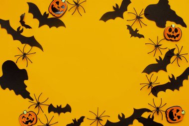 Cadılar Bayramı yatıyordu. Sarı arka planda yarasalar, örümcekler, hayaletler ve balkabağı süslemeleri. Mutlu Cadılar Bayramı! Cadılar Bayramı şablonu, mesaj için boşluk. Çerçeve düzeninde şenlikli dekor