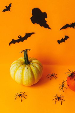 Mutlu Cadılar Bayramı! Balkabağı ve hayaletler üzerinde siyah örümcekler, turuncu arka planda yarasalar. Modern cadılar bayramı hala hayat. Metin için alanı olan kart şablonu