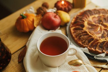 Tarçınlı, mumlu, sonbahar yapraklı, balkabaklı ve fındıklı taze elmalı turta ile sade ahşap masada, şık bir fincanda ılık çay. Sonbahar kızarıklığı hala hayattadır. Atmosferik konforlu ev