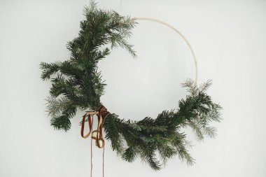 Mutlu Noeller ve mutlu tatiller! Beyaz arka planda kadife kurdeleli ve altın zilli modern Noel çelengi. Kış tatili dekorasyonu, karamsar bir görüntü. Boho çelengi