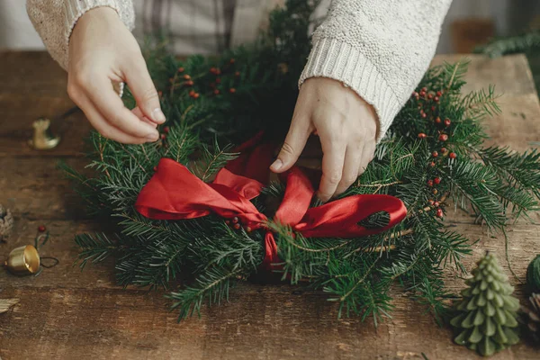 Mulher Mãos Decorando Grinalda Natal Com Fita Vermelha Mesa Madeira — Fotografia de Stock