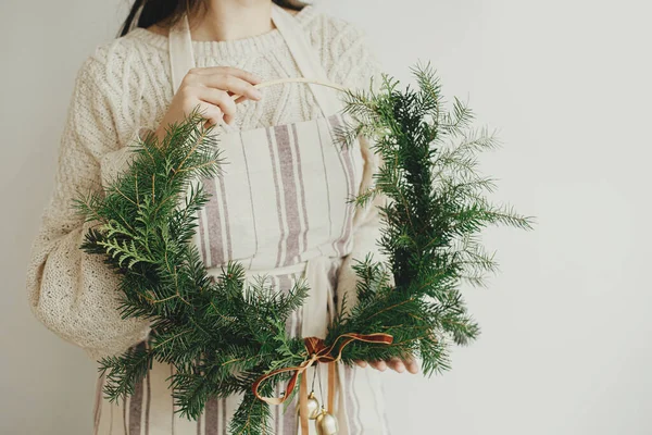 女人带着时髦的现代圣诞花环 带着丝绒丝带和金色的铃铛在白墙的背景上 假日装饰 喜怒无常的形象 圣诞快乐及节日快乐 — 图库照片