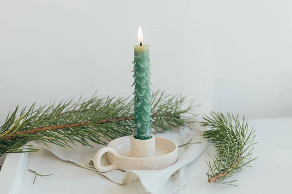 用冷杉枝条和亚麻布铺在白的乡村桌子上 像冷杉树一样 是别致的圣诞烛光 手工制作的现代绿色蜡烛 假期来了圣诞快乐及节日快乐 — 图库照片