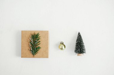 Mutlu Noeller! Havalı bir ekolojik Noel hediyesi kutusu, altın mücevher ve beyaz masa üzerindeki ağaç süslemesi. Köy tahtasında basit bir el işi Noel hediyesi. Sıfır kayıp tatil