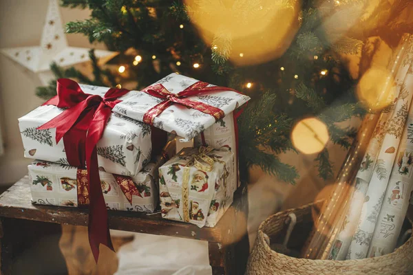 黄金のライトボケとクリスマスツリーでスタイリッシュなクリスマスプレゼント 部屋の装飾された木の下に赤いリボンで包まれたクリスマスプレゼント 大気圏イブ 休日のバナー メリークリスマス — ストック写真