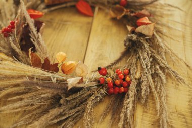 Kurumuş çimenlerle, böğürtlenlerle, ahşap masada otlarla dolu kırsal sonbahar çelengi. Çiftlik evinde sonbahar dekorasyonu ve düzenleme. Şükran Günü. Kırsal masadaki şık sonbahar çelenklerinin ayrıntıları.