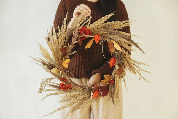 乾燥した草 ハーブや女性の手で葉でスタイリッシュなBoho秋の花輪 白い壁の背景に素朴な花輪を保持スタイリッシュな女性 農家の秋の装飾と配置 — ストック写真
