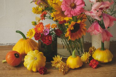 Stylish autumn composition against rustic background. Colorful autumn flowers, pumpkins, pattypan squashes still life. Seasons greeting card. Harvest in countryside. Happy Thanksgiving