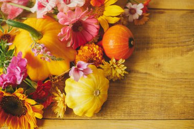 Happy Thanksgiving! Colorful autumn flat lay with flowers, pumpkins, pattypan squashes on wooden table. Seasons greeting card template with space for text. Harvest time in countryside. Hello Fall