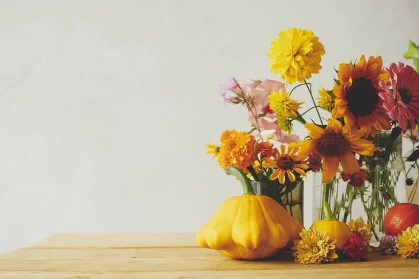 Happy Thanksgiving! Colorful autumn flowers, pumpkins, pattypan squashes composition on wooden table against rustic background. Seasons greeting card, space for text. Hello Fall