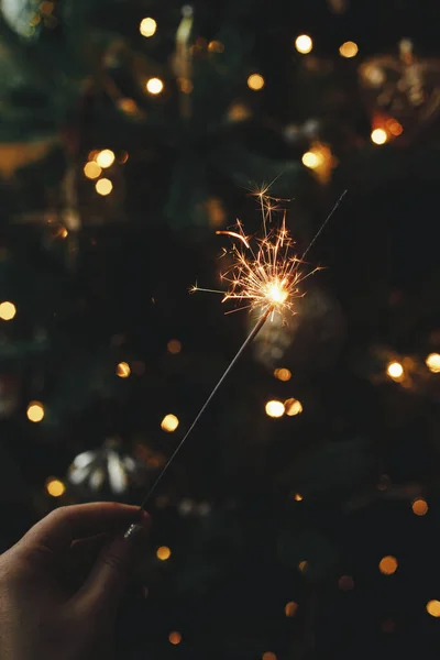 Ruka Drží Ohňostroj Proti Vánoční Stromeček Světla Tmavé Místnosti Šťastný — Stock fotografie