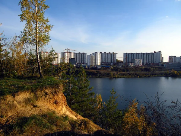 Birch, kumlu bir uçurumun kenarında, su deposunun karşı kıyısında yapım aşamasındaki çok katlı binaların arka planında.