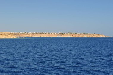 Denizden kıyı şeridine kadar panoramik manzara. Kumlu sahildeki evler. Açık güneşli gün.