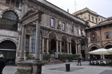 Meydandaki eski taş ev. Penceresinde sütunları ve insan figürleri olan bir ev. 14 Ekim 2014, Milan, İtalya.