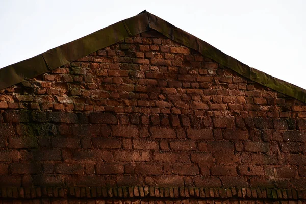 View of the roof of an old brick house. The gable of the roof is made of red brick.