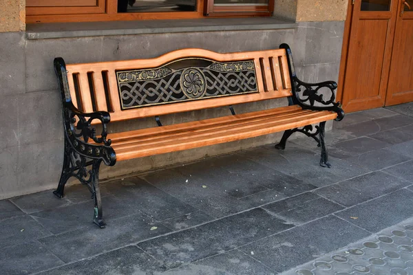 一张用木板做的漂亮的城市长椅 这条长椅的底座是用黑色铸铁做的 这条长椅的背面是由铸件和木料做成的 — 图库照片