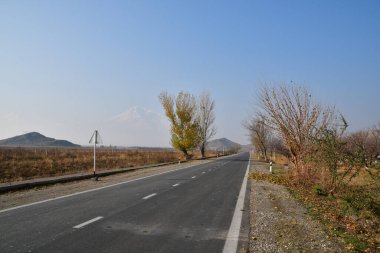 Asfalt yolunun panoramik manzarası ve Ararat Dağı 'nın karlı zirveleri. Güneşli bir sonbahar günü.