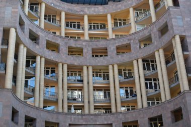 Geniş kolonları olan yarı dairesel bir bina manzarası. Balkonları olan güzel bir ev..