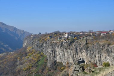 Güneşli bir günde dağların manzarası. Dağın tepesindeki evler. Dik uçurumun manzarası.