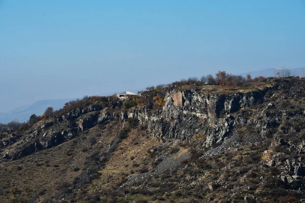 Panoramic view of the mountains on a clear sunny day. Lonely house on top of a mountain.