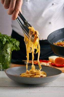 Bir şef tsuivan geleneksel Moğol yemeğine et sebzeli makarna koyar.