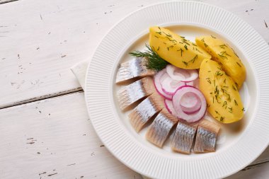 Kırmızı soğan tabağıyla dilimlenmiş salamura fileto balığı.