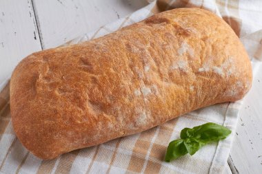 ciabatta, buğday unundan yapılan beyaz İtalyan beyaz ekmeğidir. Beyaz ahşap zemin üzerinde tuzlu zeytin yağı.
