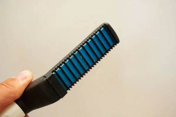 Beard straightener comb in man hand close up view