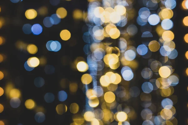 Noel ışıkları. Xmas. Yeni yıl kutlamaları mavi, altın ve siyah arkaplanı bulanıklaştırdı. Parlak arka plan, doku. Bokeh.