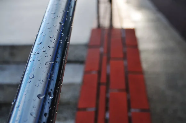 Close up of a handrail covered by rain.