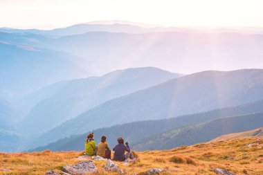 Bir tepede oturan yürüyüşçüler Karpatlar 'ın dağ vadisinin tadını çıkarıyorlar. Özgür Ukrayna 'nın vahşi doğası. Ukrayna bayrağının renkleri. 