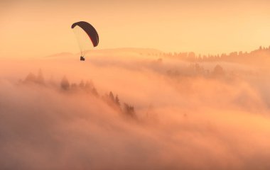 Özgür Ukrayna Karpatları üzerinde uçan Paraglide silueti. Sabah manzarası, güzellik puslu görüntü, fantastik manzara..