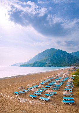 Cirali sahilinde bir sürü şezlong ve hasır şemsiyeler. Akdeniz kıyısı, Türk, Lycia.
