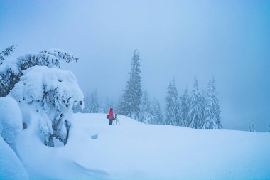 Photographer with the camera on a tripod waiting for the sunlight in a snowy winter landscape.