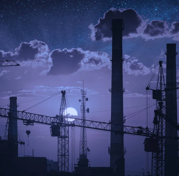 産業風景の上に満月の上昇 星空に対するクレーンや工場パイプの構築 — ストック写真