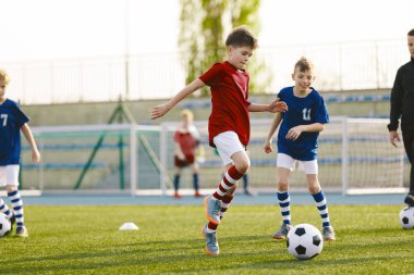 Kırmızı ve Mavi Futbol tişörtlü genç sporcular. İki Çocuk Balo için yarışıyor. Spor Eğitimi. Futbol sahasında Çocuklar Futbolcuları Top Tekmeliyor. Spor Futbolu Yatay Arkaplanı