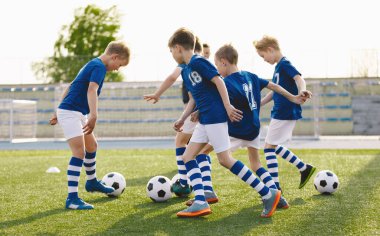 Mavi Futbol formalarıyla Futbol Takımı Toplarla Eğitim Sınıfında. Çocuklar Çimen Meydanı 'nda Topları Tekmeliyor. Okul çocukları için futbol sınıfı