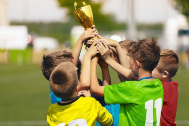 Futbol Takımı Kutlaması. Neşeli Çocuklar Futbol Turnuvasında Başarı Kutlaması. Genç Spor Takımı Konfeti Kutlamasında Yükselen Altın Kupa. Zıplayan ve neşeyle top atan çocuklar.