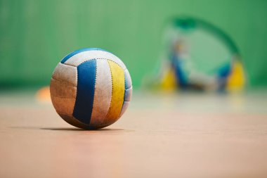 Tahta kortta voleybol. Spor topu kapalı stadyum parketinde yatıyor.